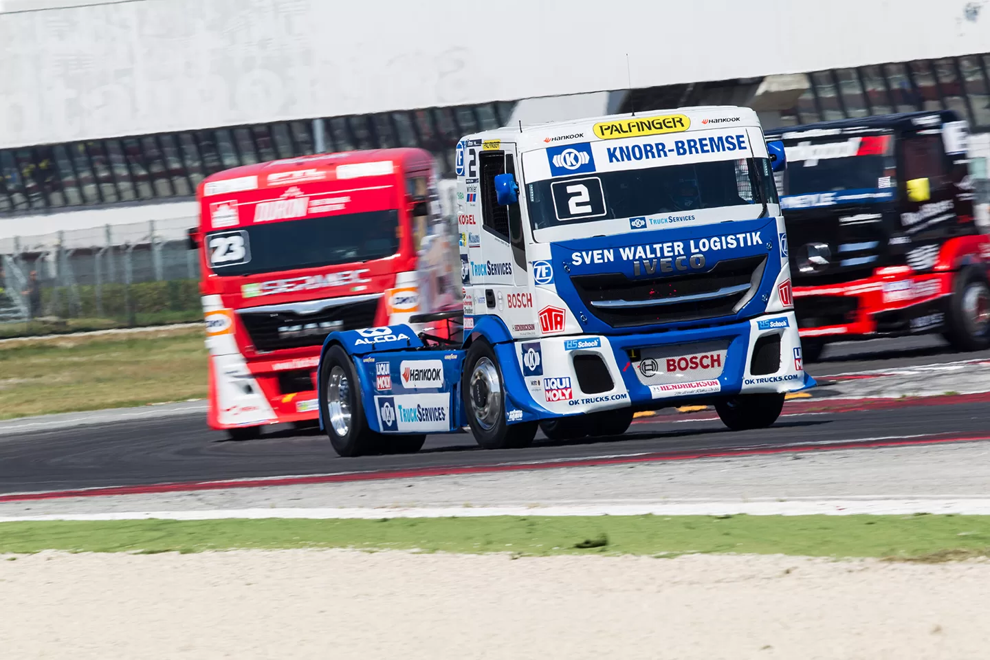 Blue truck racing three other trucks on a track