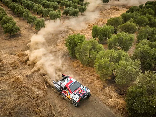 Car going around corner on dirt track with trees