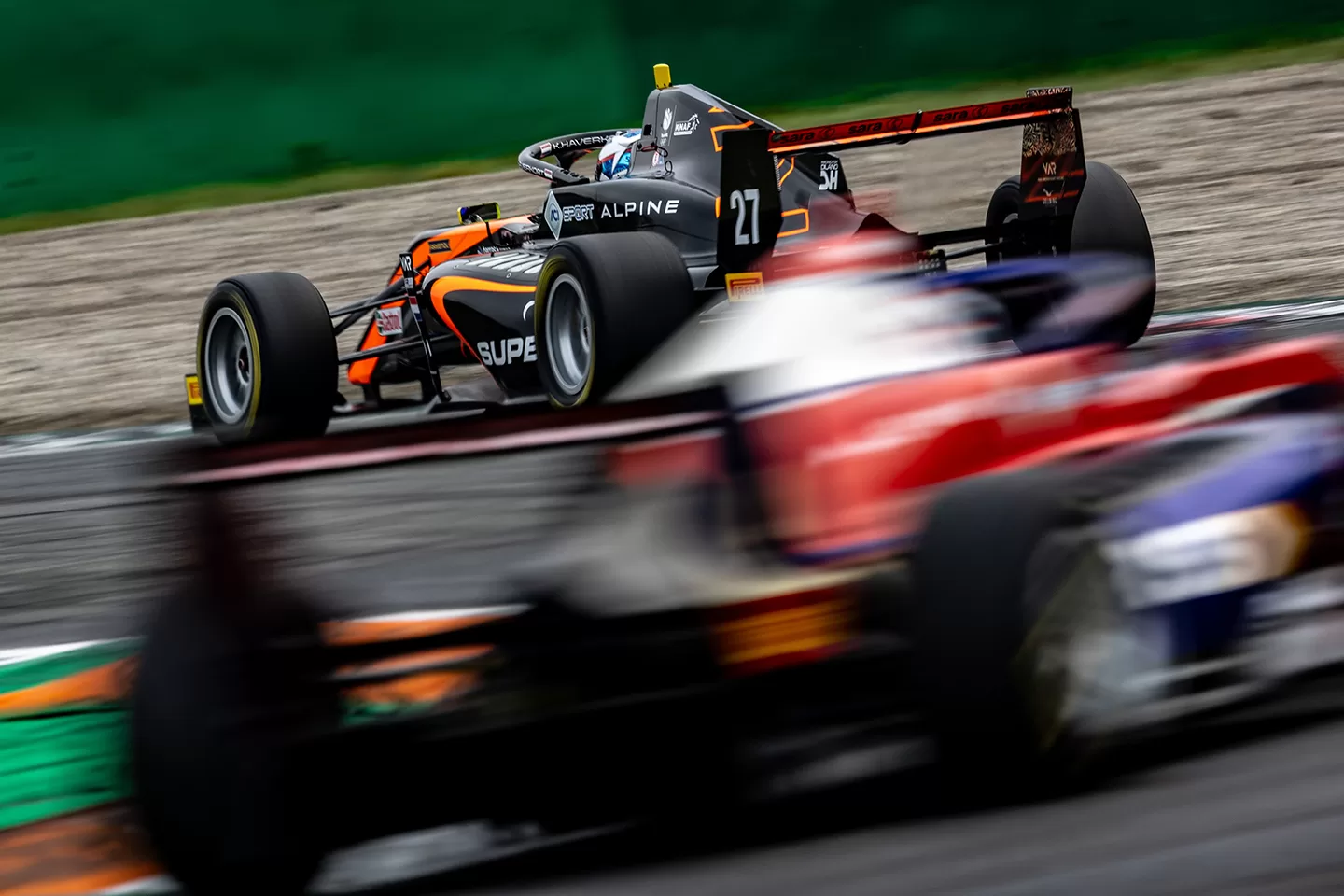 Two racing cars battling it out, with one blurry and one in focus 