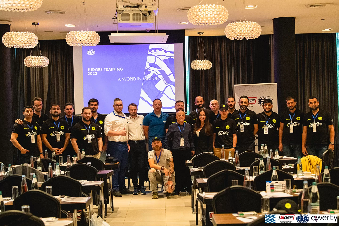 Group of men and women dressed in black standing in front of a screen with 'judges training' written on it