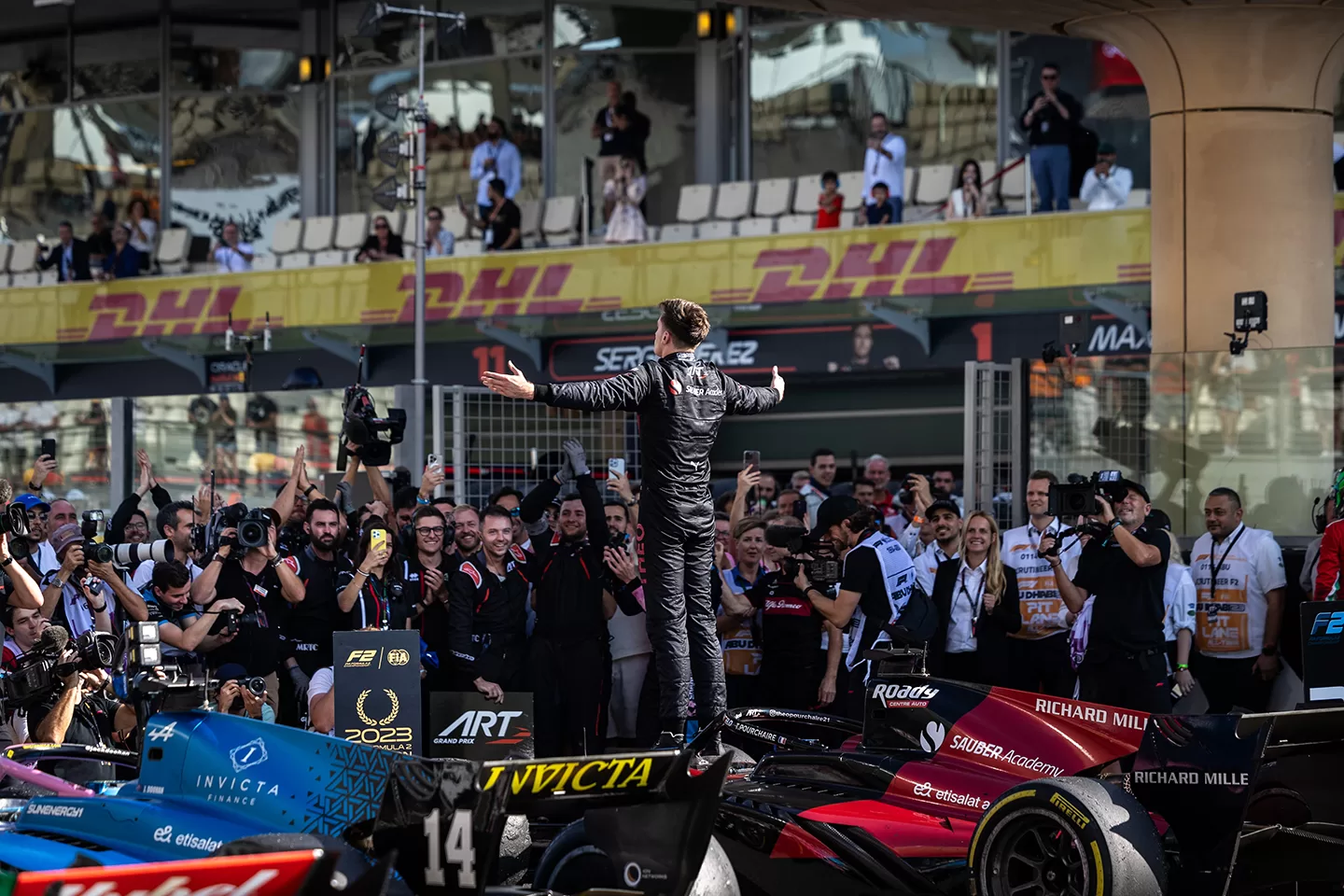 Racing driver stood on top of his car with arms outstretched