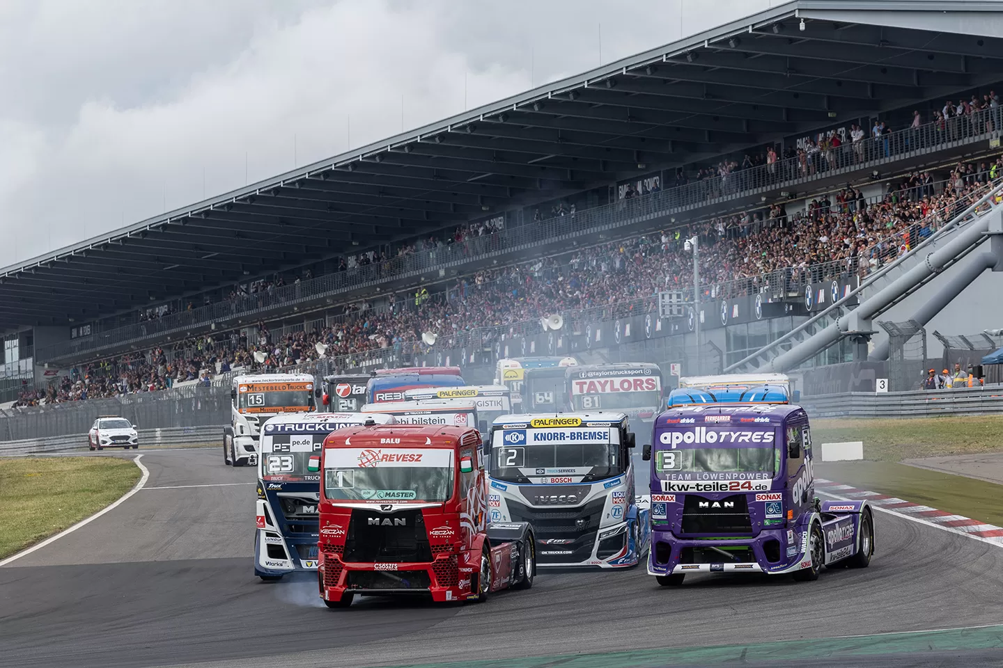 Group of variously colourful trucks racing on a track