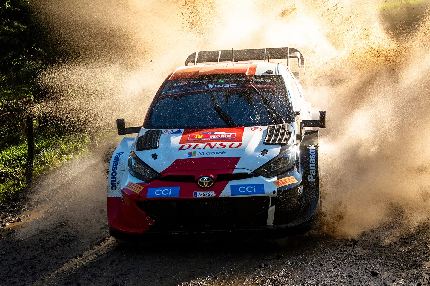 Red and white car on a track with dust behind it