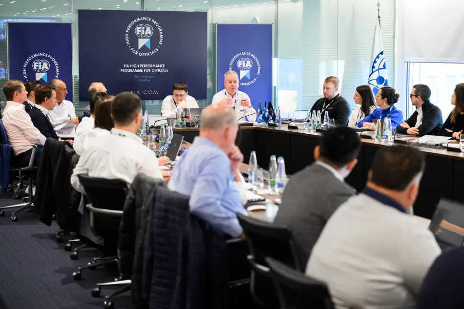 Group of people speak sat around a black table with blue banners behind them