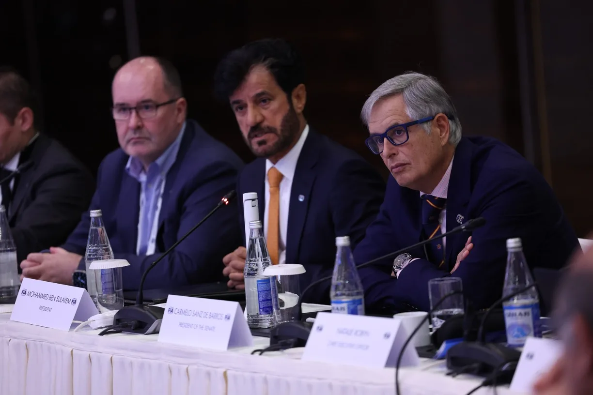 President Mohammed Ben Sulayem with Robert Reid and Carmelo Sainz Barros sat at conference desk with microphones and glasses of water